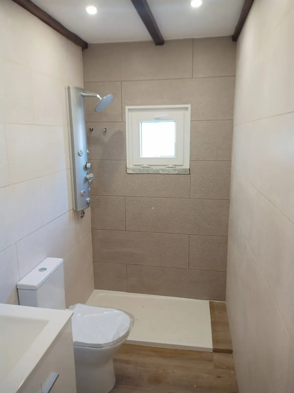 Casa de banho com coluna de duche, base de duche, sanita e móvel de lavatório