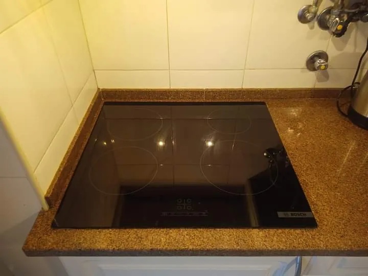 Placa de indução preta encastrada numa bancada de granito