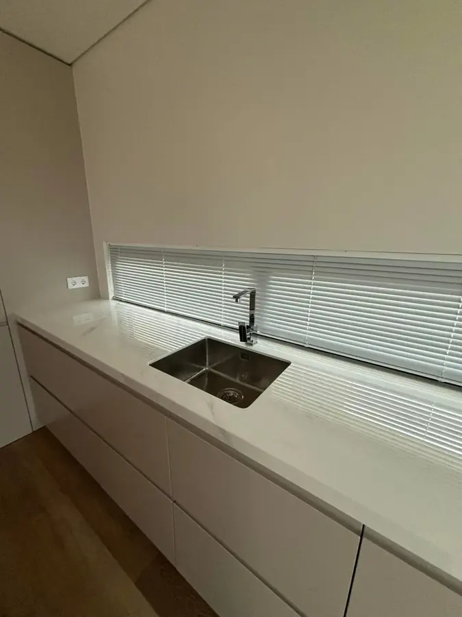 Estore laminado de alumínio numa janela comprida por cima da bancada da cozinha