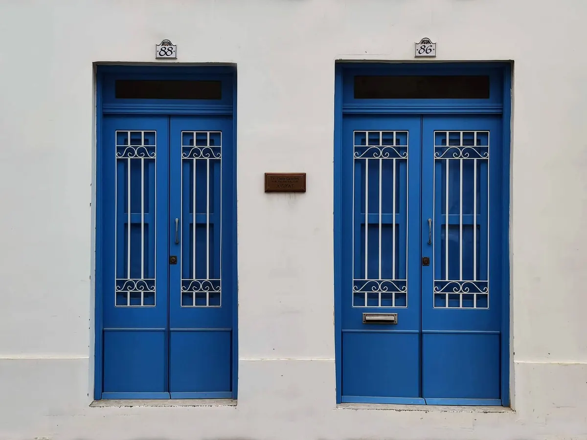 Duas portas azuis numa parede branca