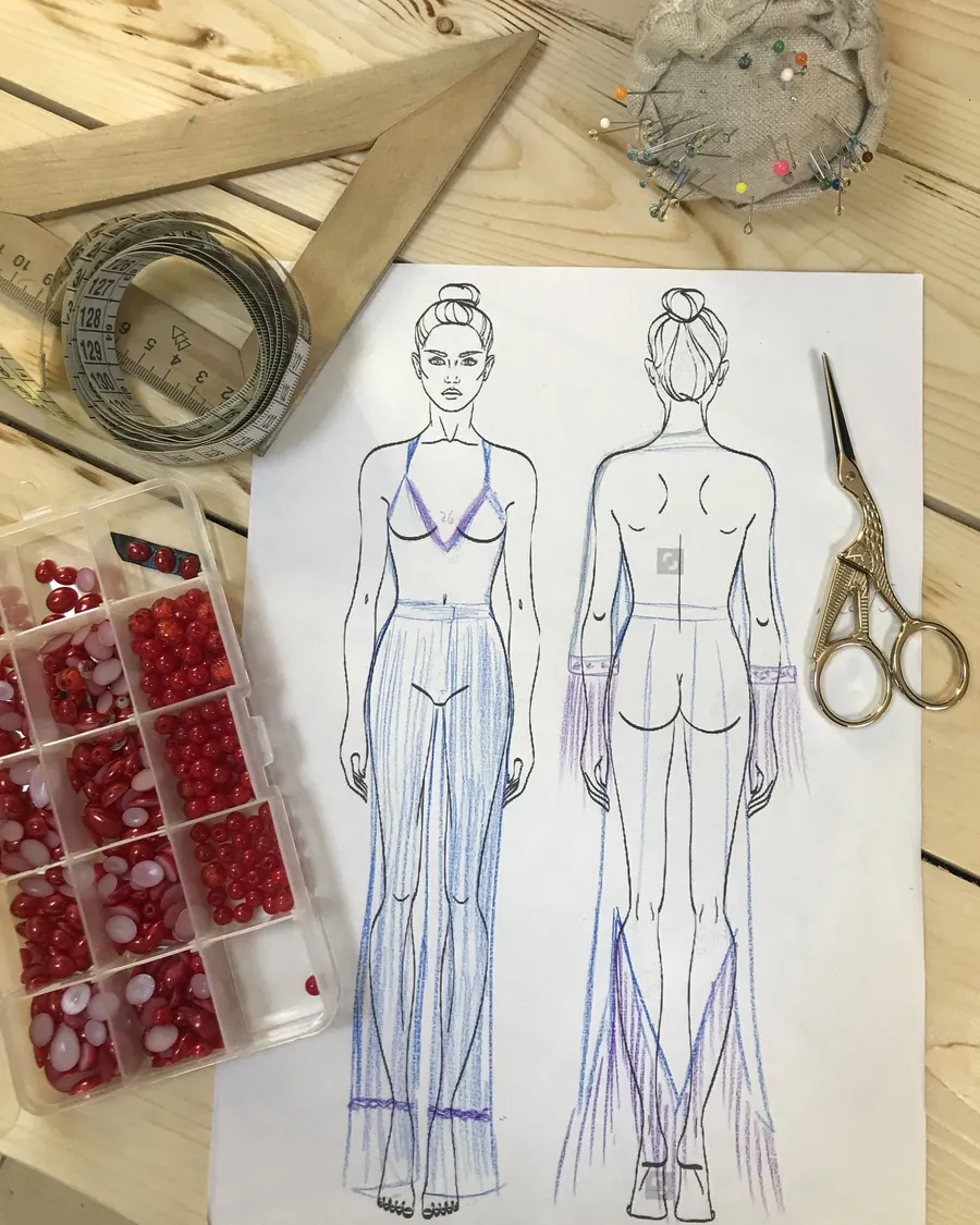 Croqui de um vestido, de frente e de costas, com tesoura, alfinetes e fita métrica à volta.