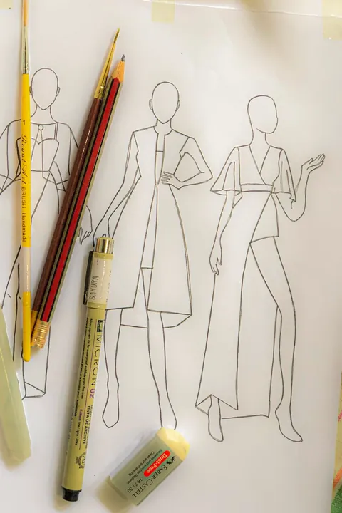 Croquis de vestidos a lápis, com os lápis de cor por cima.
