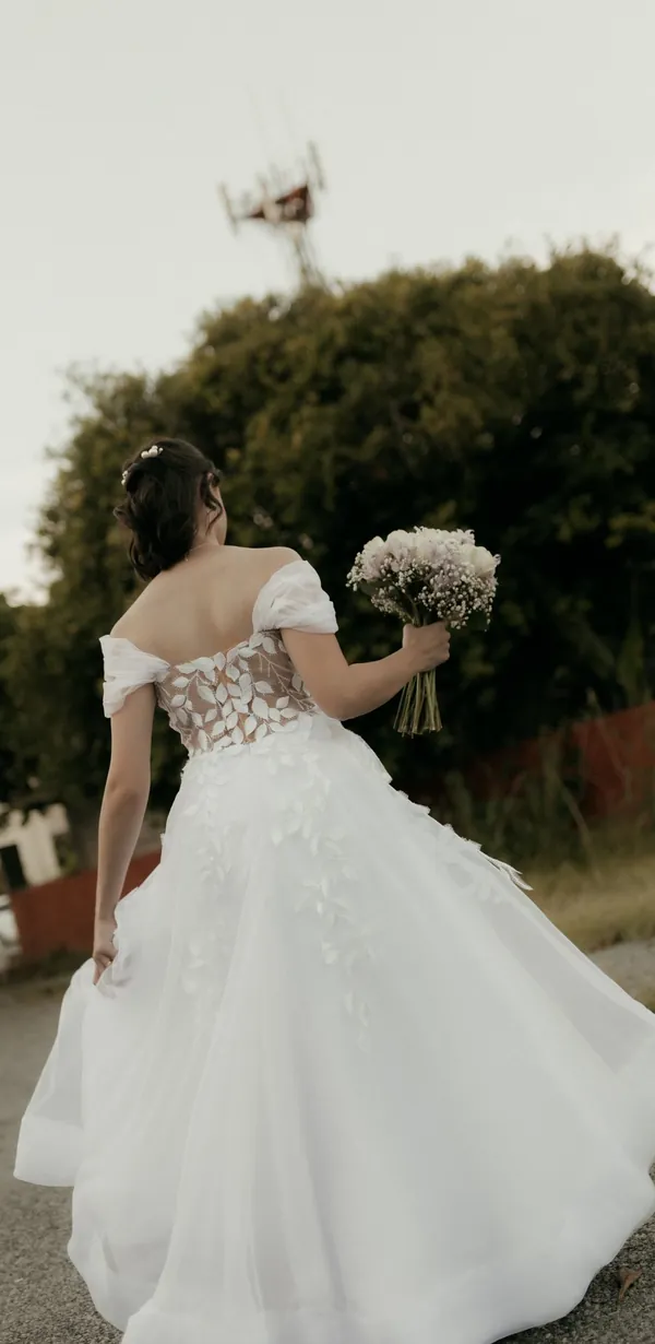 Vestido Jasmim de costas, ao ar livre: corpete de renda e saia rodada de tule.