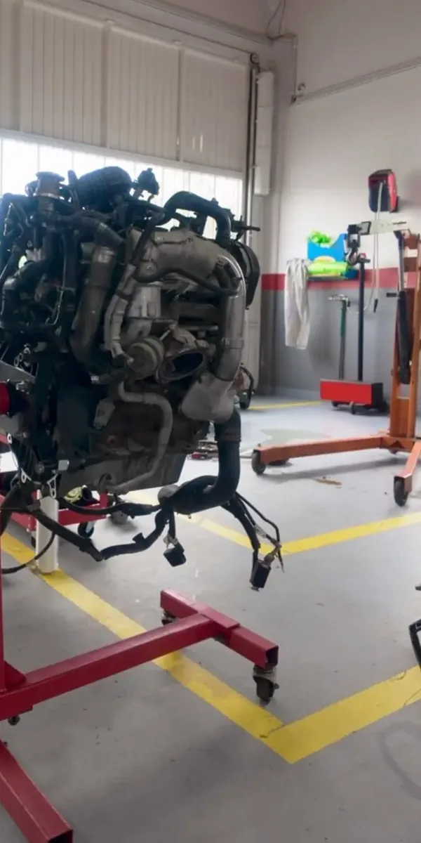 Motor retirado do automóvel, num suporte de oficina vermelho